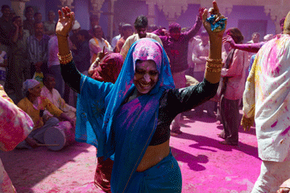 北方邦的一名妇女在洒红节彩云中跳舞。”border=