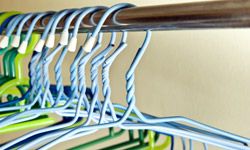 Multicolored wire clothes hangers hanging from a bar in a closet