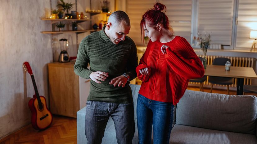 A young couple in love dancing in the living room at night.