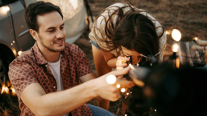 Couple stargazing together with a astronomical telescope while being on a romantic date