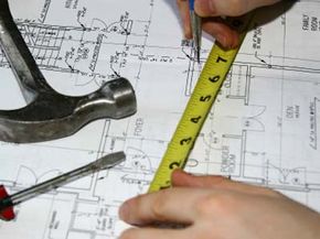 Builder taking measurements and adjustments on blueprint.