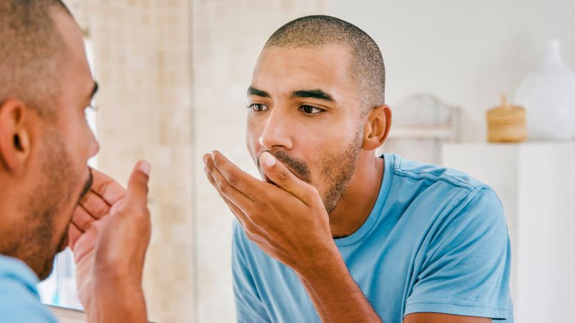 A man checking his breath in a comfort room.