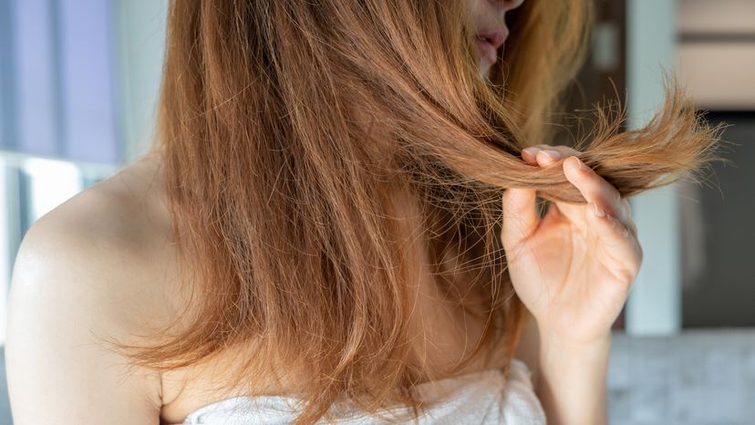 A girl on shower checking her frizzy and dry hair.