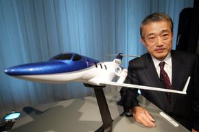 Takeo Fukui, President and Representative Director of Honda Motor Co., Ltd. stands next to a model of HondaJet at a media conference on Dec. 17, 2003 in Tokyo, Japan.