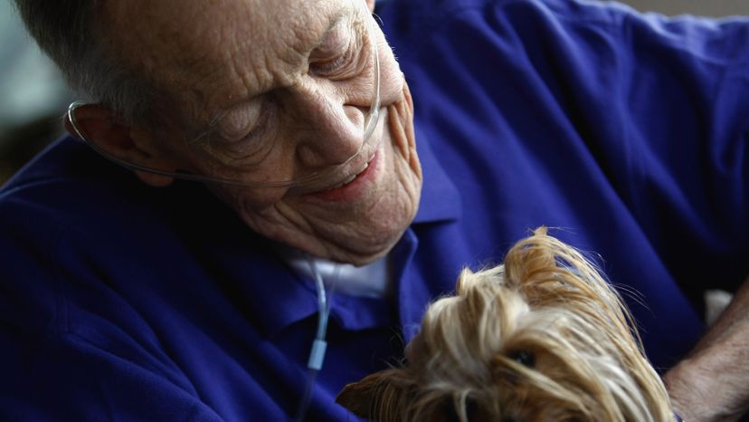 2009年8月31日，巴德·安德森在家中接受临终关怀时，抱着一只名叫萨利·苏的治疗犬。约翰摩尔/盖蒂图片社＂border=
