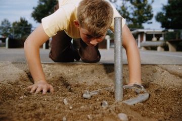 Young boy inspecting a horseshoe game