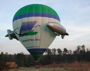 A blue, green and white hot air balloon is on the ground, preparing to take off.