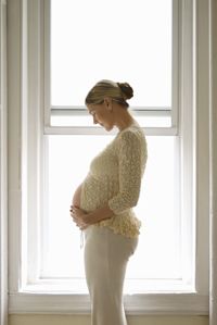A pregnant woman in front of a window.