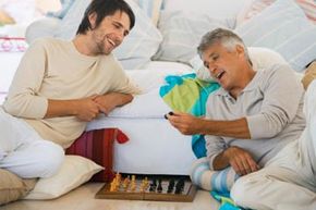 caucasian man and adult son playing chess and laughing