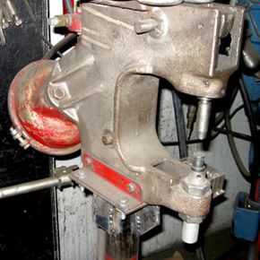Close-up of a pneumatic riveter. The anvil is held in the bottom of the riveter and the roller is above it. Brake and lining would slide between the anvil and roller to be riveted together.