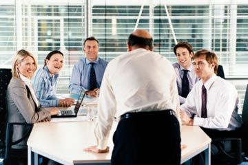 Business Executives Smiling at a CEO in a Boardroom Meeting