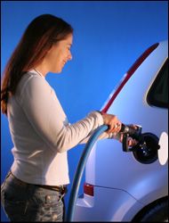 Woman smiling as she pumps gasoline into her car.