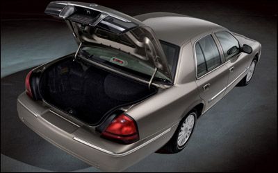 A four-door sedan parked on a grey background with its trunk open.