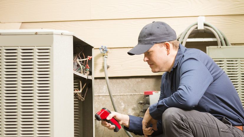 Air conditioner repairmen work on home unit.