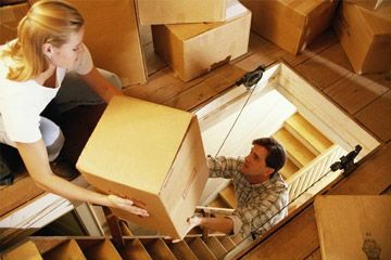 Couple moving boxes into attic, elevated view.
