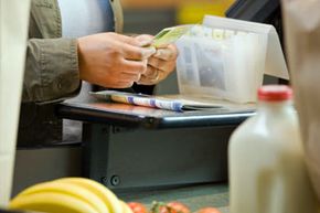 Woman sorting coupons at supermarket, close-up, mid section.