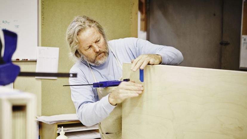 A man glues and clamps two pieces of wood together.