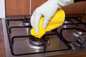 gloved hand scrubbing gas range