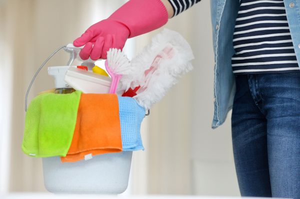 person holding a bucket of cleaning supplies