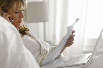 woman in bed with computer, phone and papers