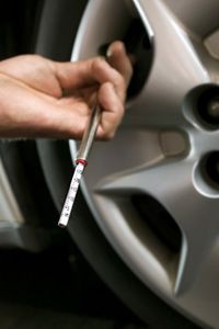 Checking tire air pressure with a pressure gauge