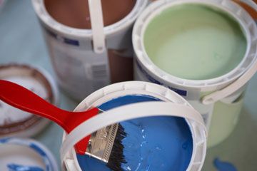 Open cans of paint with paintbrush