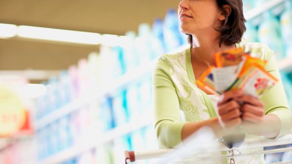 A lady holding coupons while grocery shopping 