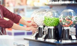 Side profile of a teenage couple taking candy in a candy store