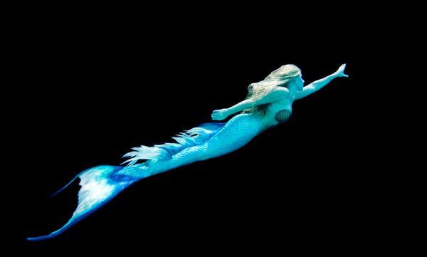 Woman in mermaid costume swimming