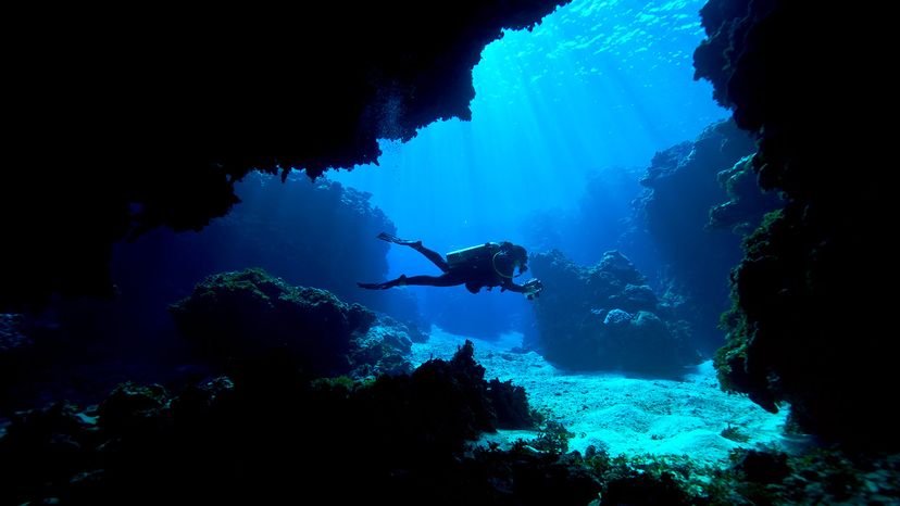 scuba diver exploring an underwater cave in a tropical coral reef.