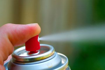 person depressing nozzle of spray paint can