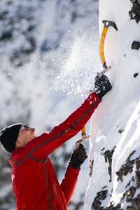 A Colorado ice climber plants his ice tool in the ice.