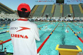 A Chinese swimming coach watches his swimmers train from the pool deck in Perth, Australia.