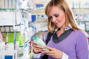 Portrait of blonde woman reading label of shampoo in pharmacy. Copy space