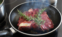 Meat cooking in a pan with a garnish on top.