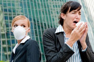 woman sneezes while woman in masks watches