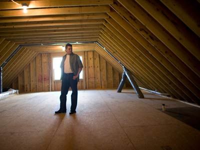 Man standing in attic under construction.