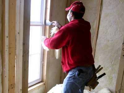 A worker insulates a window on a new construction building