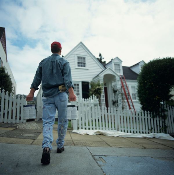 Man carrying paint toward house