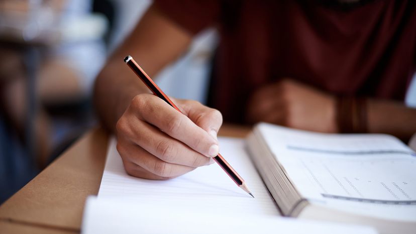 a person holding a pencil takes a written test