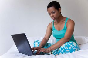 Woman typing on laptop on bed