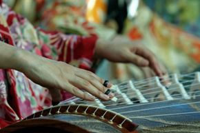 A woman plays the koto, the national instrument of Japan, which is a whopping six feet long (1.83 meteres) and has 13 strings.