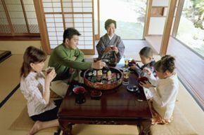 A Japanese family at dinner in their traditional wood and paper house.