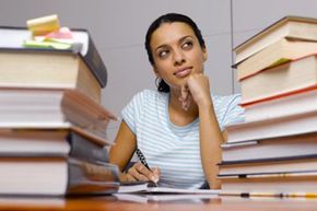 Woman pondering amid textbooks