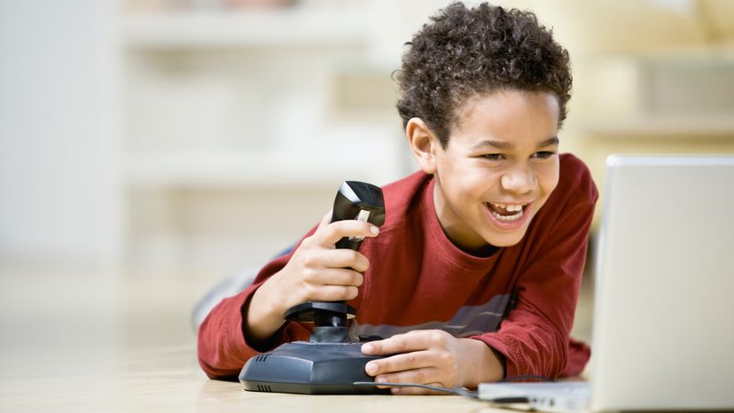 Boy playing game with a joystick on laptop