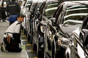 A Toyota Motor Corp. worker kneels down to check a Lexus at the Japanese automaker's flagship production line for luxury Lexus models in Tahara, central Japan.