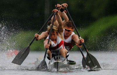 Men outdoors rowing with oars in sport.