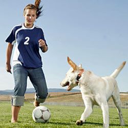 teen girl playing soccer with dog