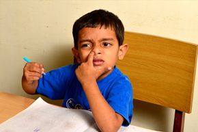 Boy picking nose at desk