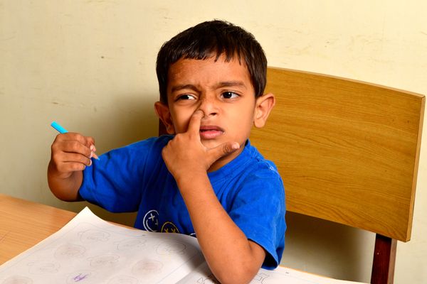 Boy picking nose at desk